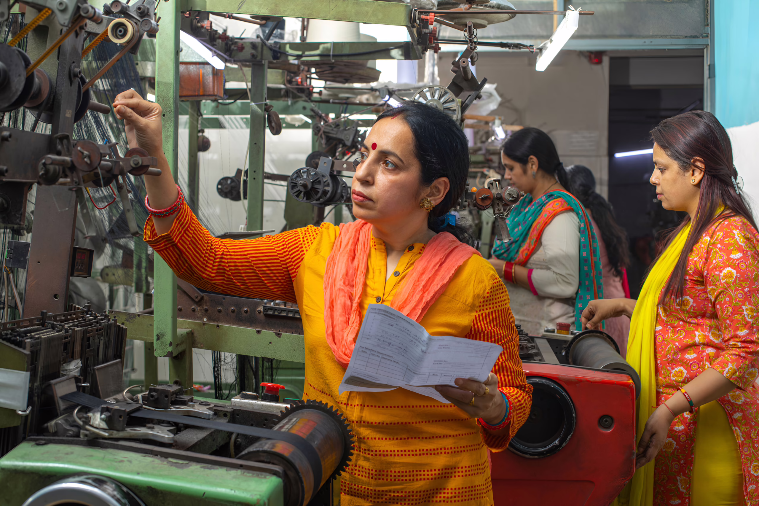 Indian woman with paper inspecting manufacturing equipments.