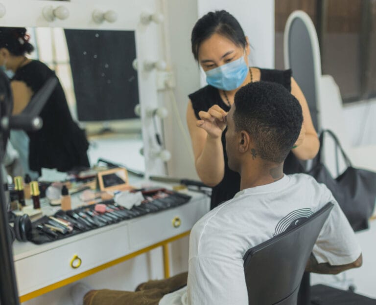 model putting makeup on in studio to prepare for the shoot