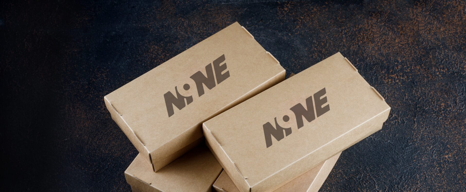 Recyclable kraft boxes with printed logo stacked on dark surface, showcasing eco-food packaging design.