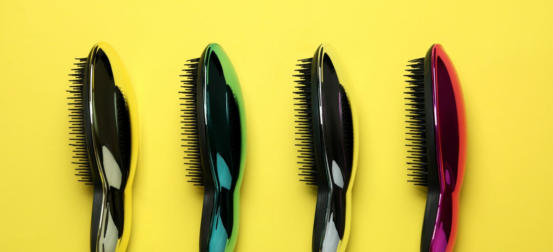 Close-up shot of multiple custom brushes with different metallic colors on a yellow background.
