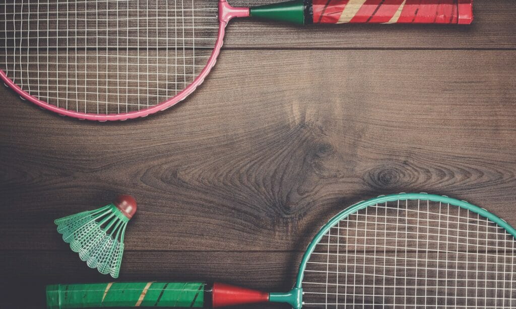 Colorful rackets and a shuttlecock showcasing essential badminton equipment on a wooden surface.
