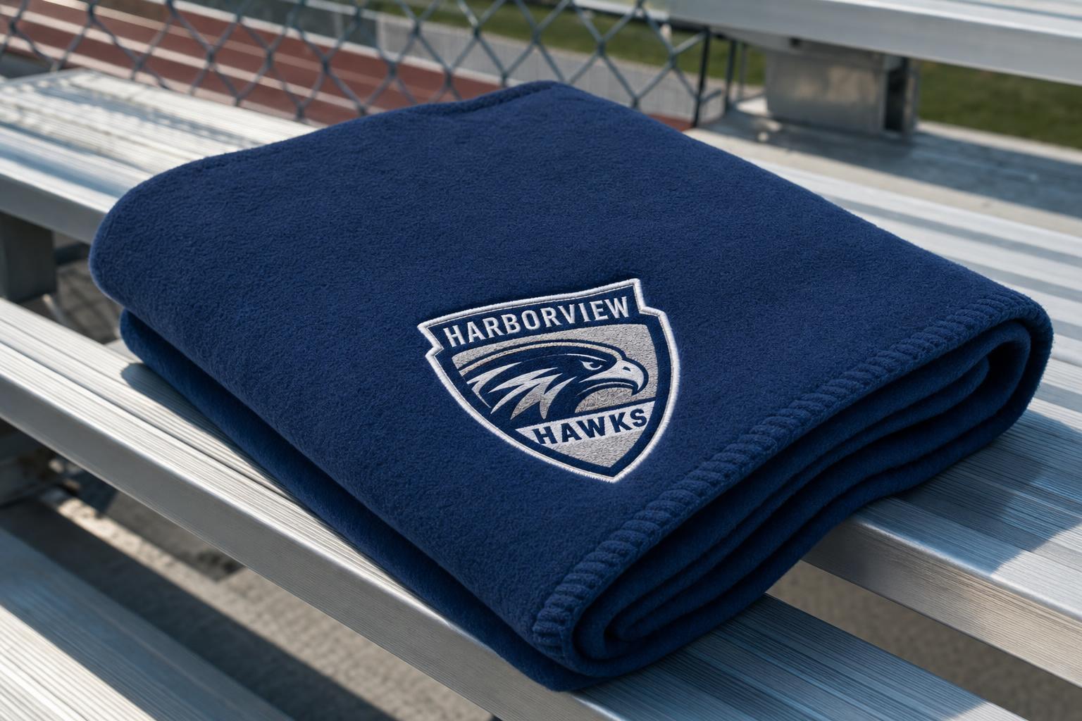 Custom branded fleece blanket with an embroidered logo on a stadium seat.