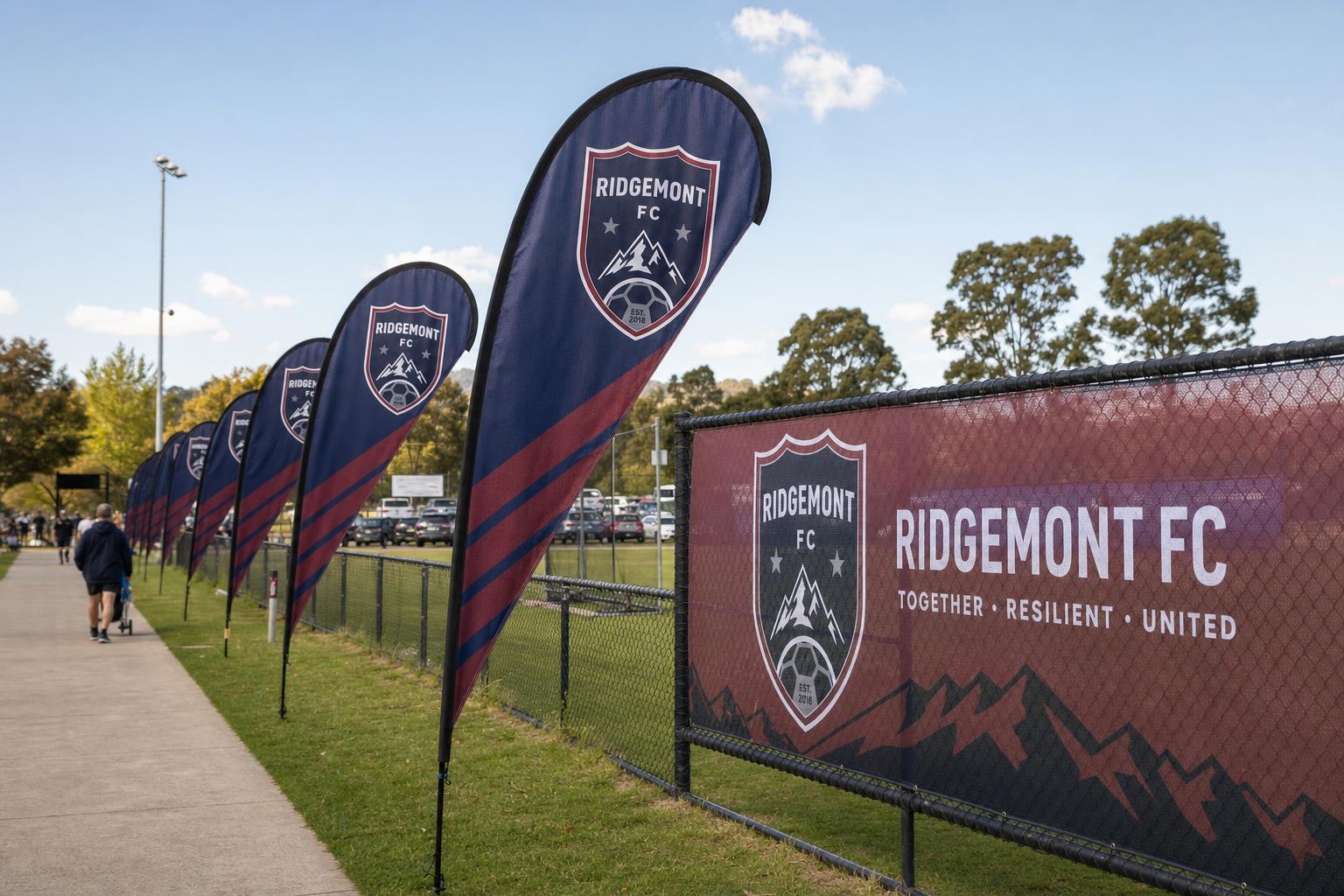 Custom branded teardrop flags and fence banner at an outdoor sports event.
